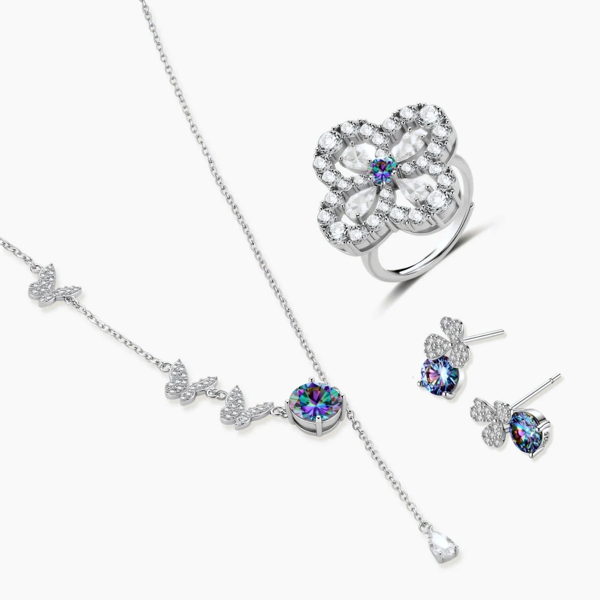 Sterling silver jewelry set with rainbow moissanite stones in clover and butterfly designs on cream background