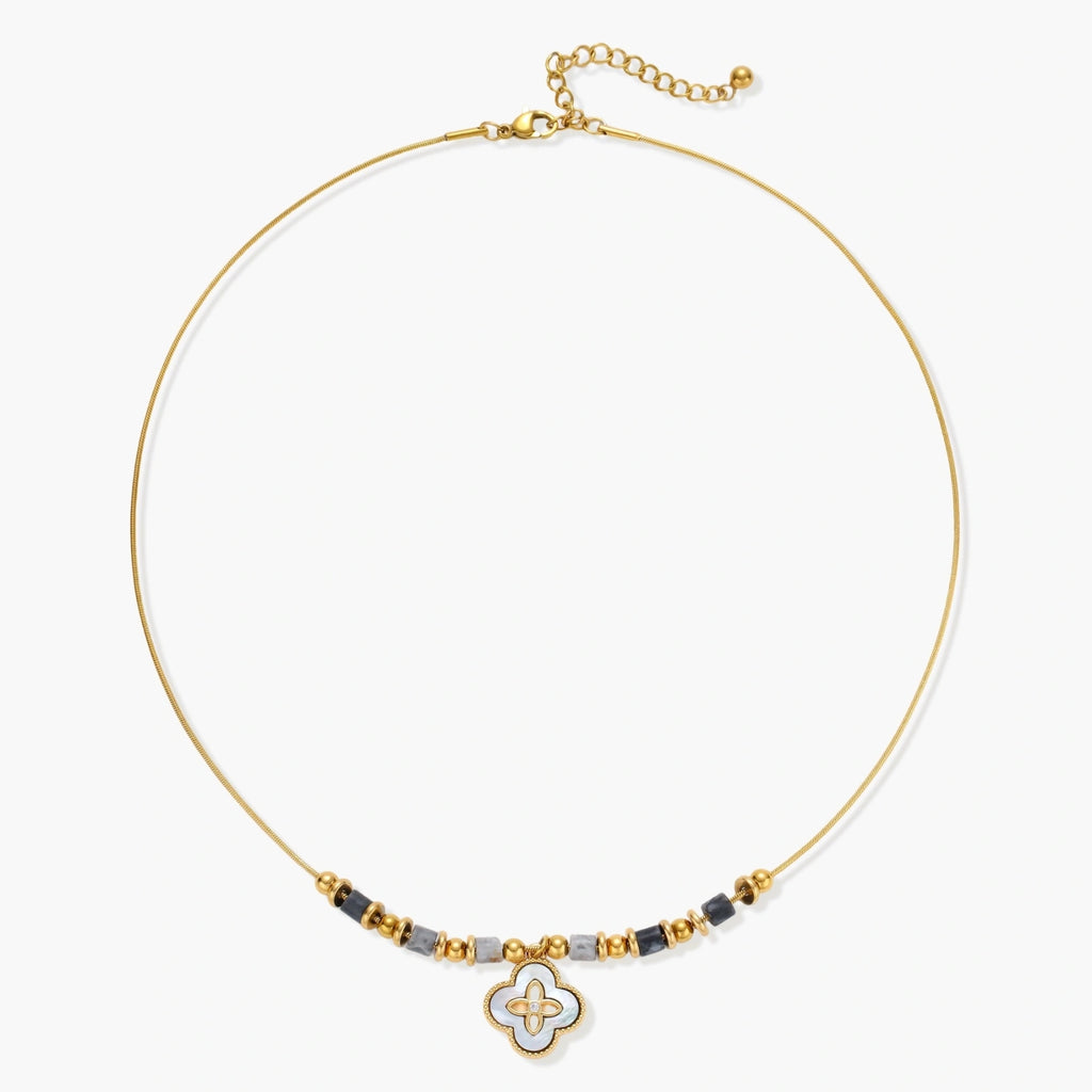 Gold-toned beaded necklace with grey stones and quatrefoil abalone shell pendant on cream background.