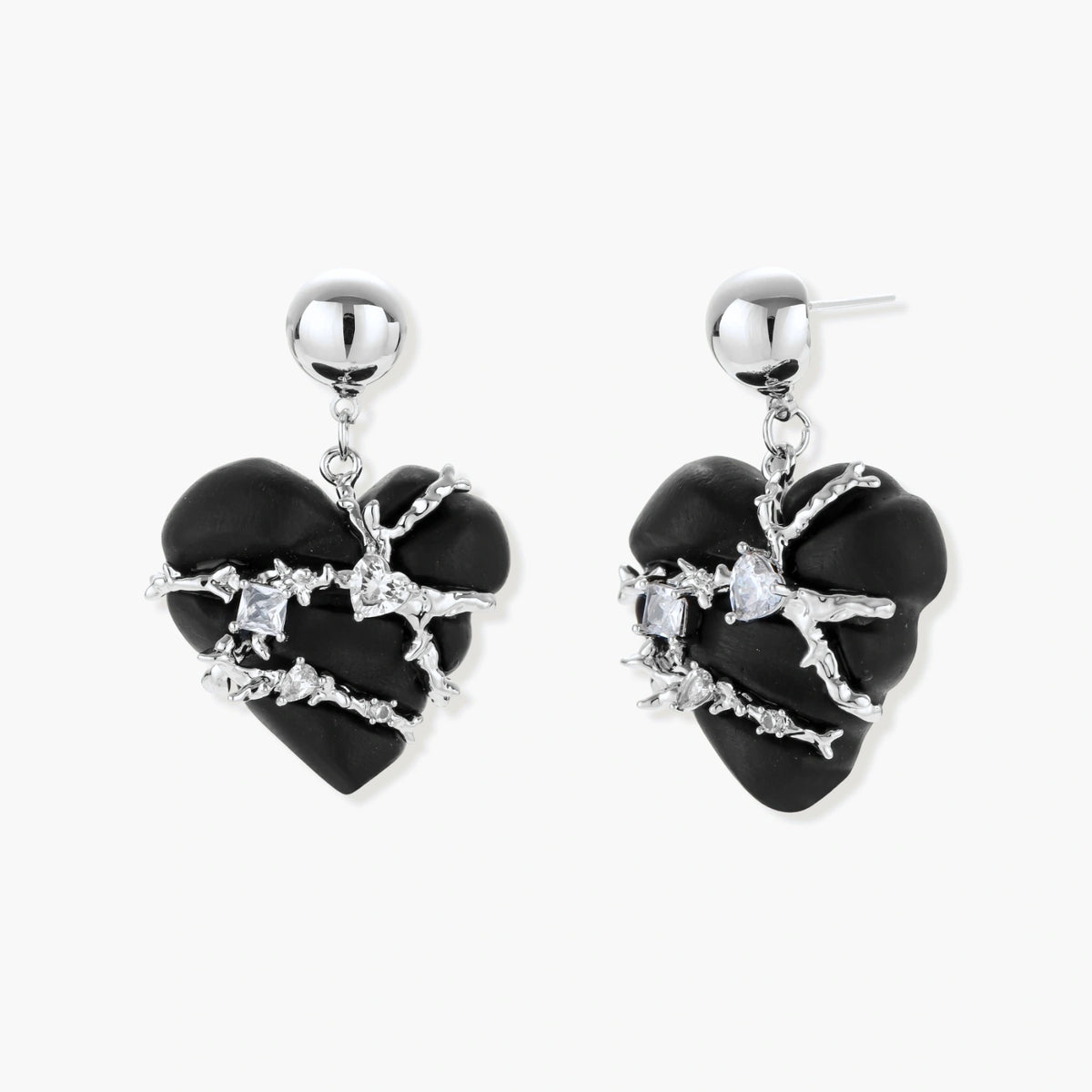Dark ebony wood heart charms wrapped in intricate silver chains with crystal accents, shown as matching earrings and necklace set.