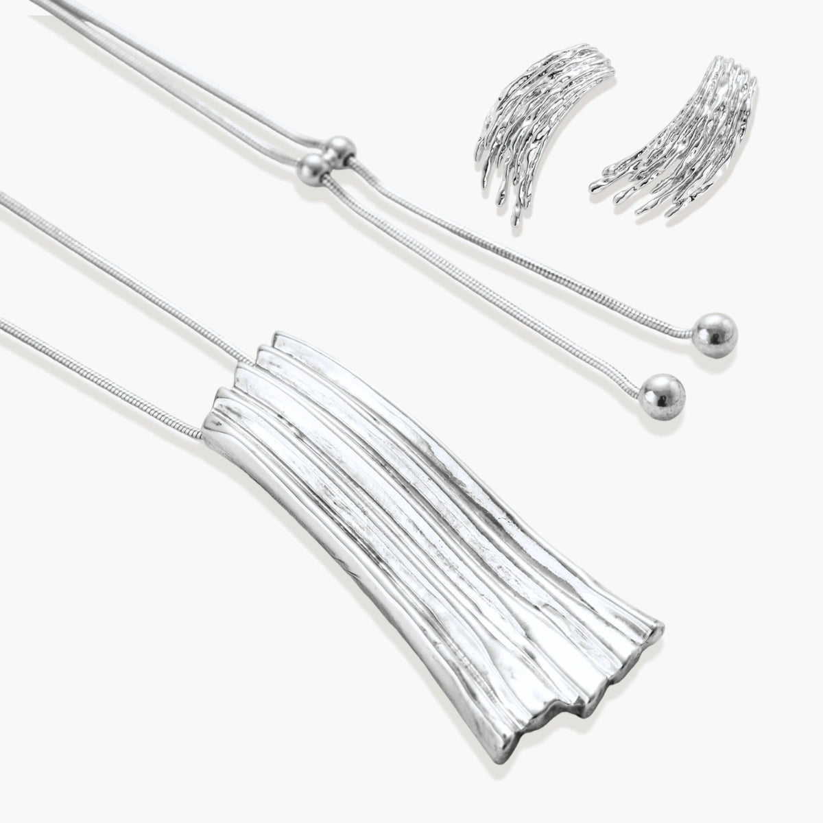 Layered metallic wing-shaped pendant and matching earrings with feathered texture in silver and gold finishes
